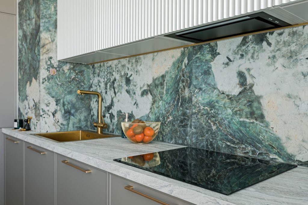 A stylish kitchen with PVC marble sheets used as a backsplash behind the sink and stove.